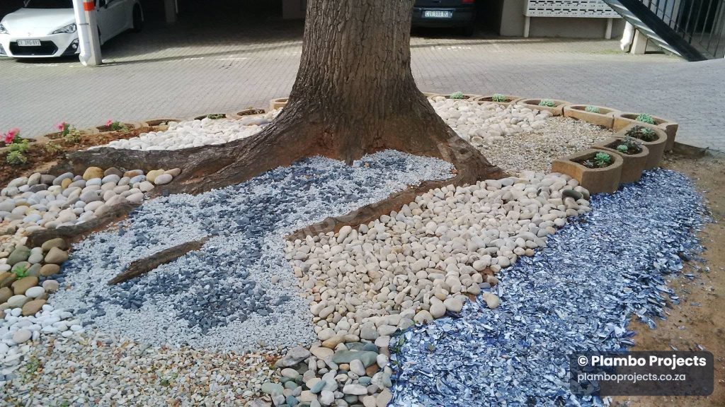 Stone landscaping around a tree by Plambo Projects